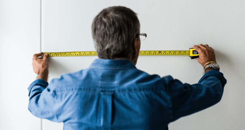 Man measuring wall with tape measure