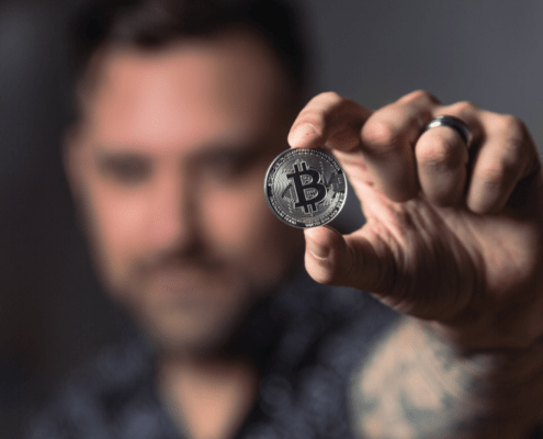 Blurred man holding coin with Bitcoin logo