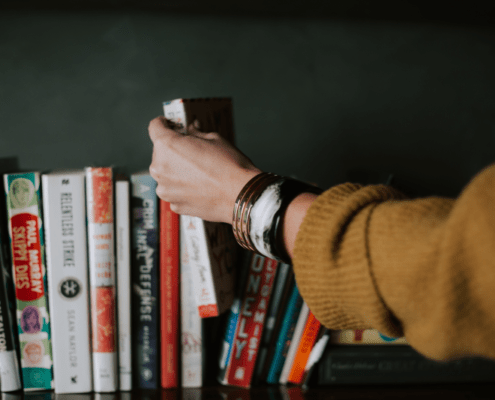 Women's hand removing a book from a shelf