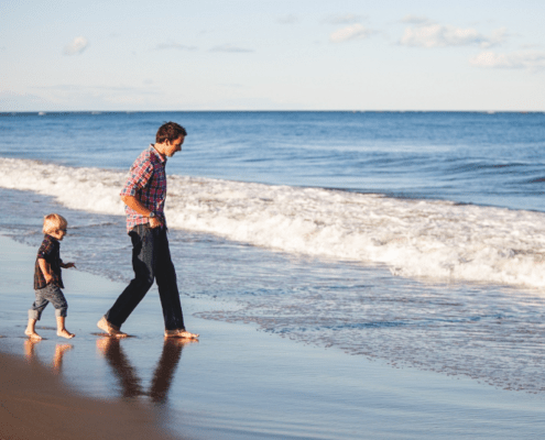 Man and young boy walking on beach