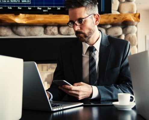 Man in a suit using laptop and phone