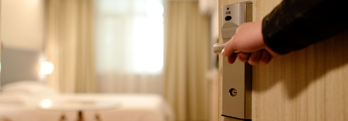 Man's hand opening up a hotel room door