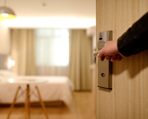 Man's hand opening up a hotel room door