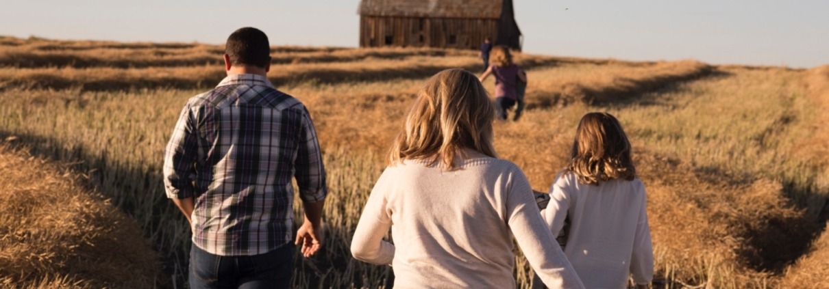 Family walking in field towards barn