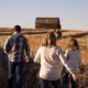 Family walking in field towards barn